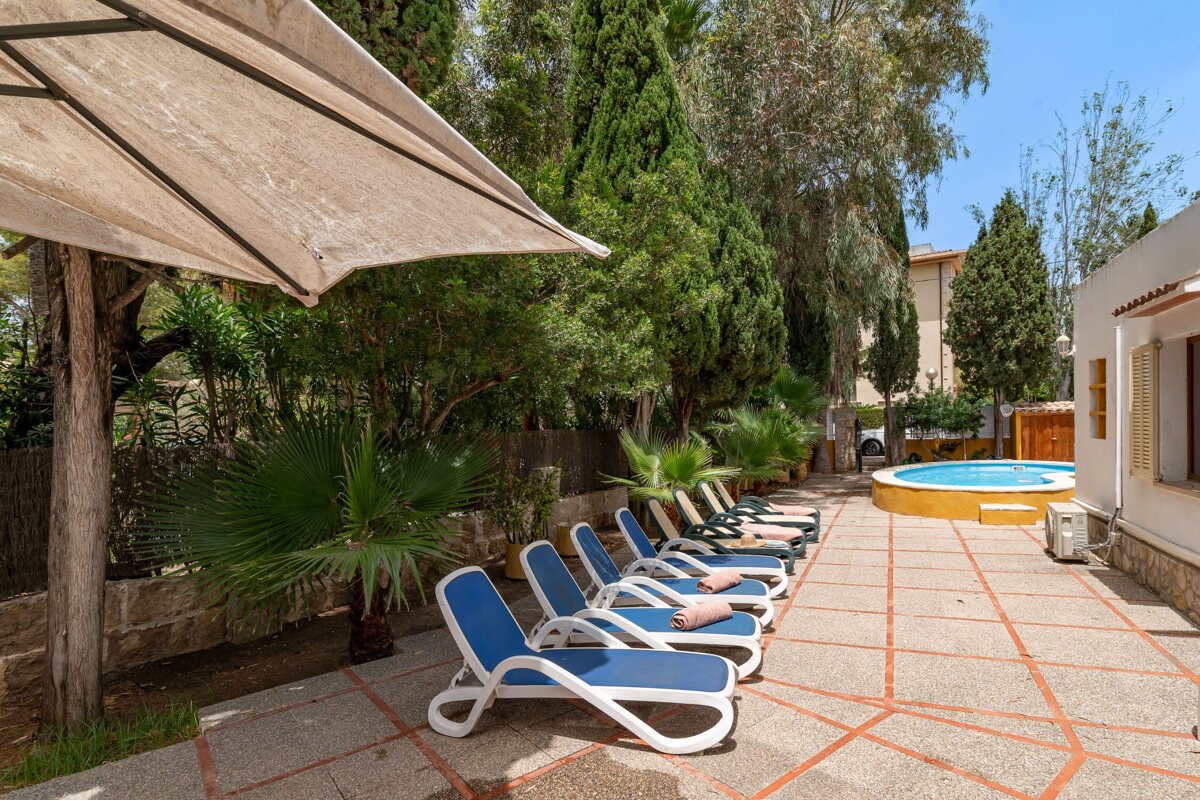 A row of blue lounge chairs sit on a patio next to a pool