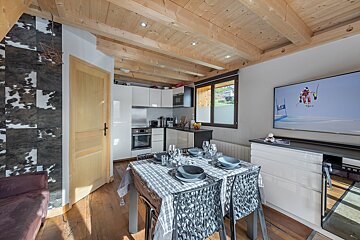 A dining room with a table and chairs and a television with a ski racer on it