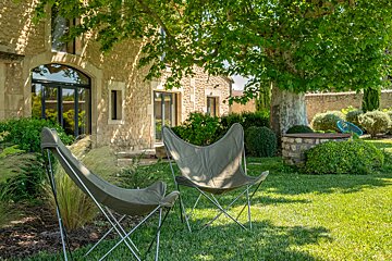 Two folding chairs sit in the grass in front of a stone building