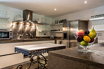 A bowl of fruit sits on a counter in a kitchen