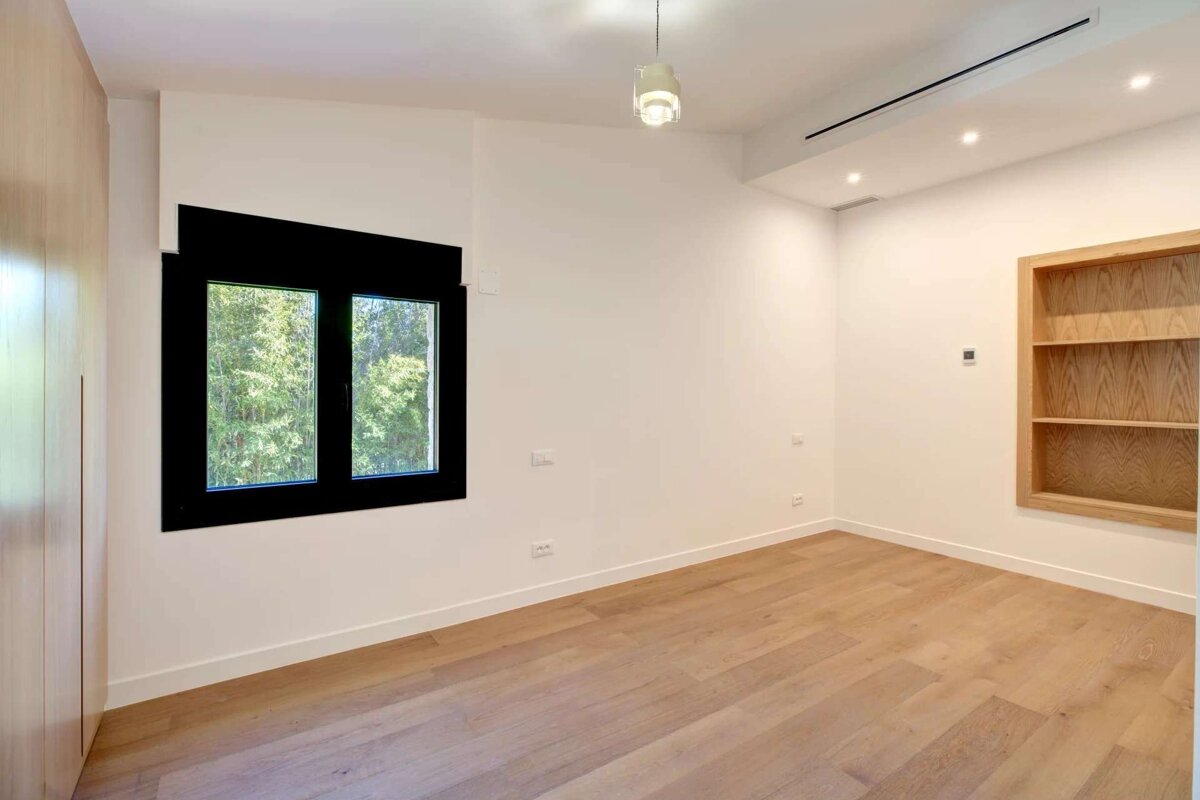 An empty room with two windows and a shelf