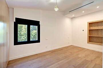 An empty room with two windows and a shelf
