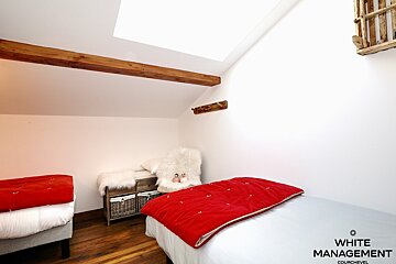 A bedroom with two beds and a rental designer logo on the wall