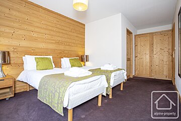 A bedroom with two beds and a sign that says alpine-property
