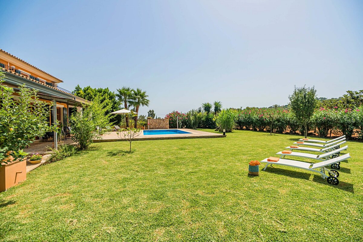 A lush green lawn with a swimming pool in the background
