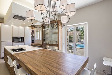 A kitchen with a large wooden table and white chairs