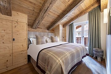 A bedroom with a wooden ceiling and a bed