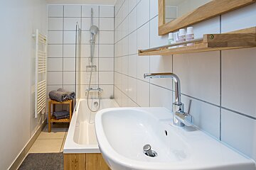 A bathroom with white tiles and a sink