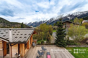 A house with a metal roof is for sale by mountain base