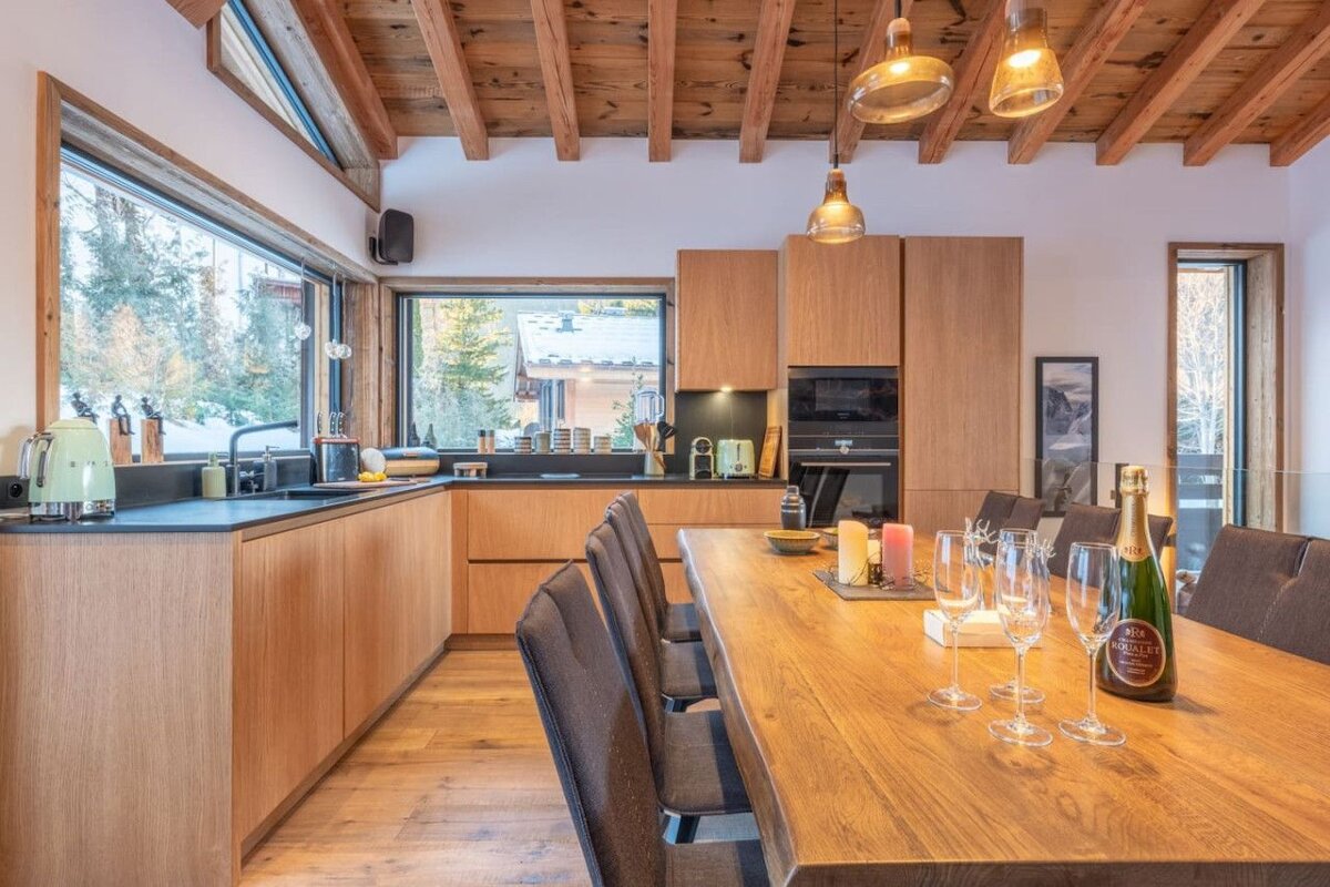 A bottle of champagne sits on a wooden table in a kitchen