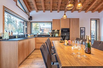 A bottle of champagne sits on a wooden table in a kitchen