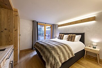 A bedroom with a large bed and a sliding glass door
