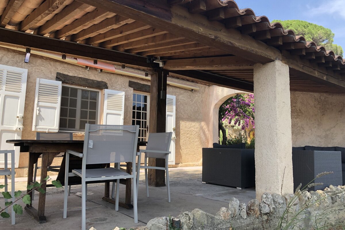 A patio with a table and chairs under a wooden roof