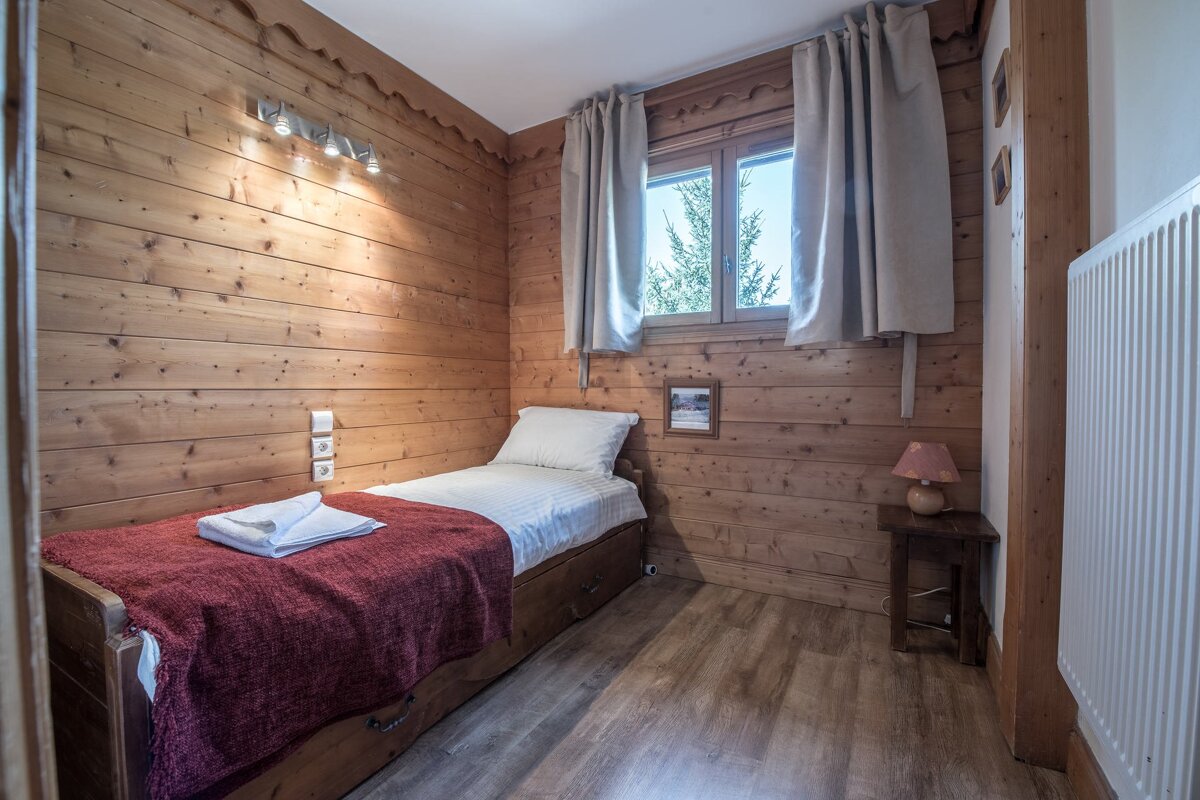 A bedroom with a single bed and a window
