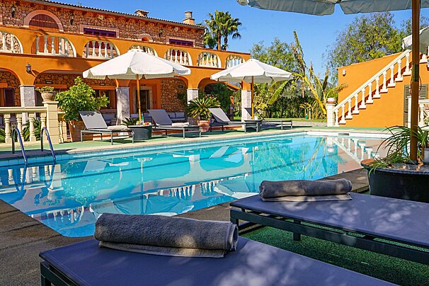 A large swimming pool surrounded by lounge chairs and umbrellas