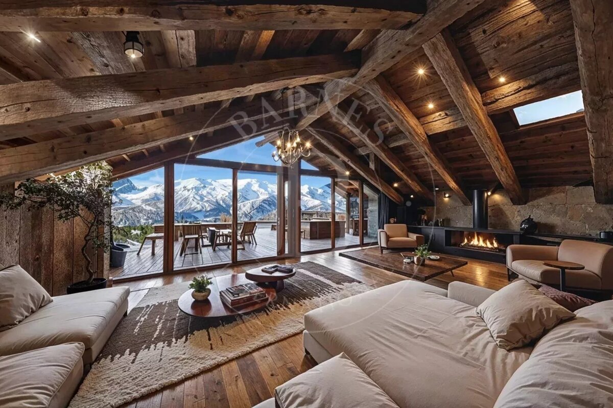 Rustic cabin attic living room with large glass doors showing snow-capped mountains.