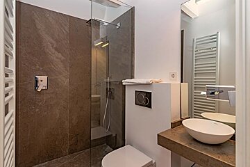A bathroom with a toilet a sink and a walk in shower