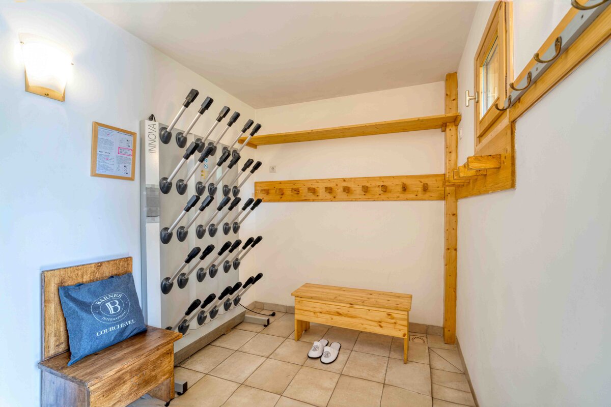 Ski room in a chalet featuring a heated boot dryer rack, wooden benches, shelves, and coat hooks.