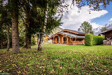 A small wooden cabin in the middle of a lush green field