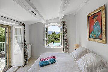 A bedroom with a painting of a man on the wall