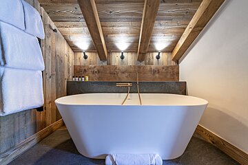 A bathtub in a bathroom with a wooden ceiling