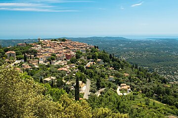 A small town sits on top of a hill surrounded by trees