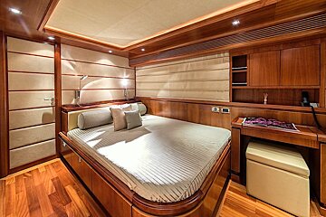 A bedroom with a bed and a desk with a magazine on it