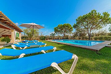 A swimming pool with blue lounge chairs and an umbrella