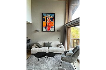 A living room with a couch and chairs and a painting on the wall