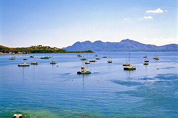 A large body of water filled with boats and mountains in the background