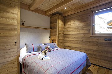 A bed with a plaid blanket and pillows in a wooden room
