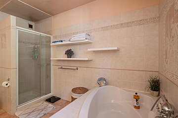 A bathroom with a bathtub a shower and shelves