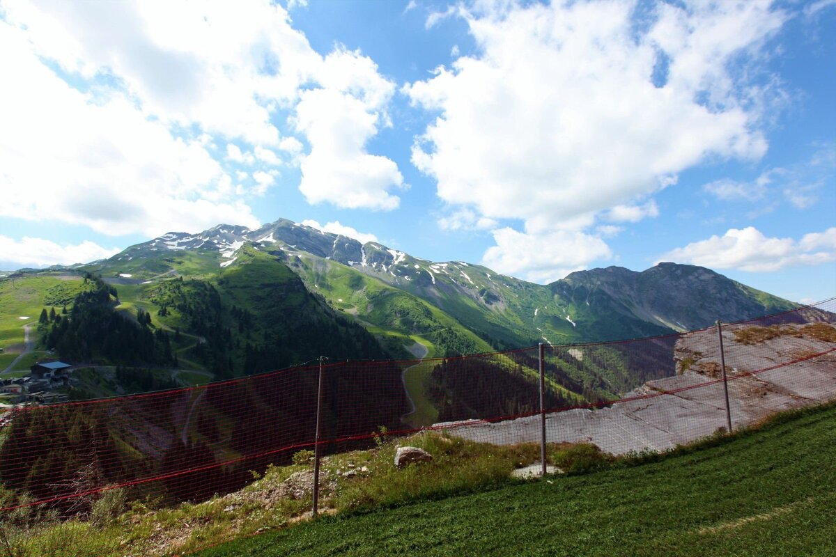 A mountain range with a red fence in the foreground