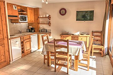 A kitchen with a table and chairs and a clock on the wall