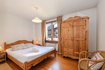 A bedroom with a wooden bed and a wooden wardrobe