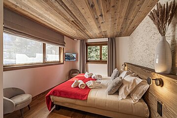 A bedroom with a wooden ceiling and a bed with a red blanket
