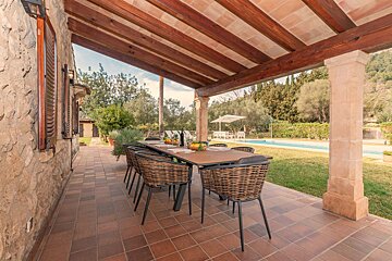 A patio with a table and chairs under a wooden roof