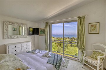 A bedroom with a sliding glass door and a view of the ocean