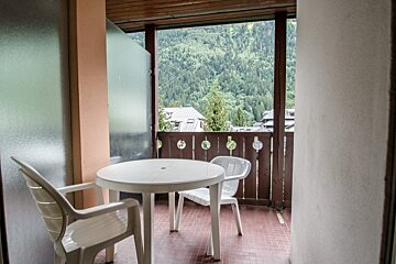 A balcony with a table and chairs and a view of the mountains