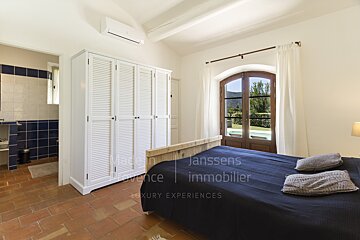 A bedroom with a bed and a wardrobe that says janssens immobilier