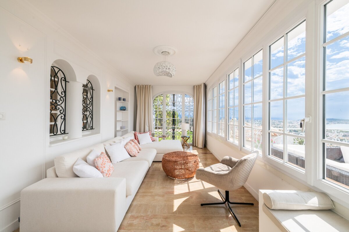 A living room with a couch and chair and lots of windows