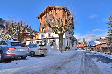 A silver audi is parked in the snow in front of a building