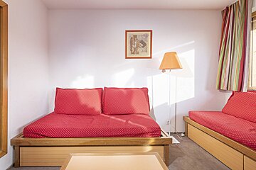 A living room with two red couches and a lamp