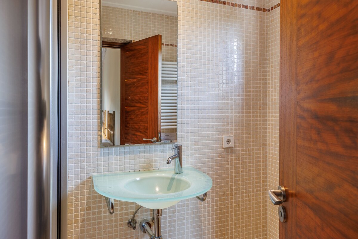 A bathroom with a glass sink and a mirror
