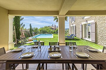 A patio with a table and chairs and a pool in the background