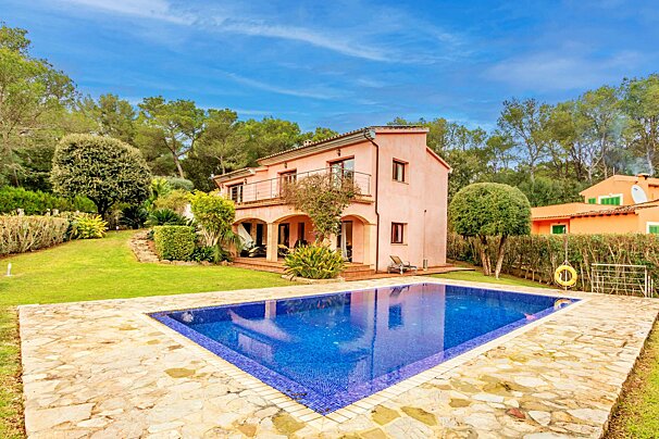 A pink house with a large swimming pool in front of it