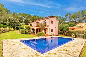 A pink house with a large swimming pool in front of it