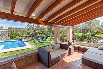 A patio with a couch and chairs and a pool in the background