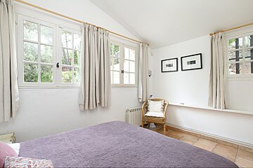 A bedroom with a purple bed and a wicker chair