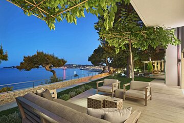 A patio with a couch and chairs overlooking the ocean